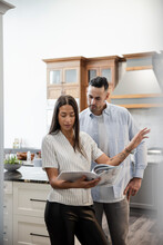 Couple Looking At Catalogue In Kitchen Showroom