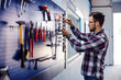 © dusanpetkovic1 - Stacking tools in the workshop. A man dressed in a casual suit stands next to a tool board and tidies up the keys. Mechanical work indoor, repairing machine and cars