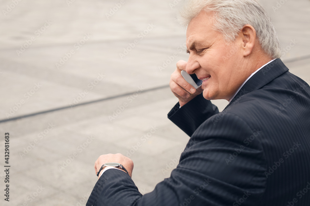 Senior businessman talking by mobile phone in park