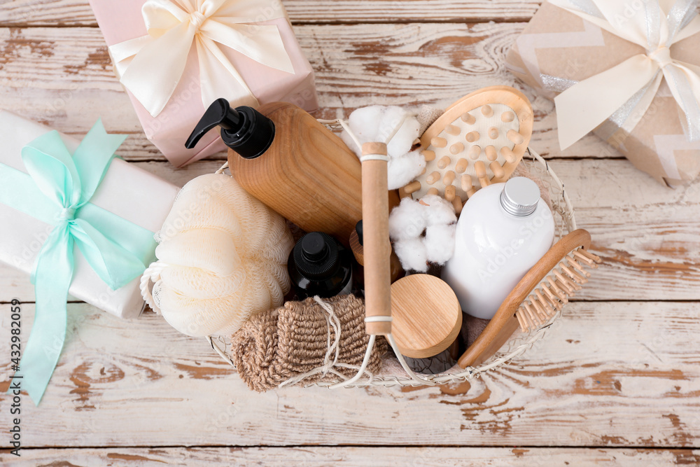 Gift basket with cosmetic products on light wooden background