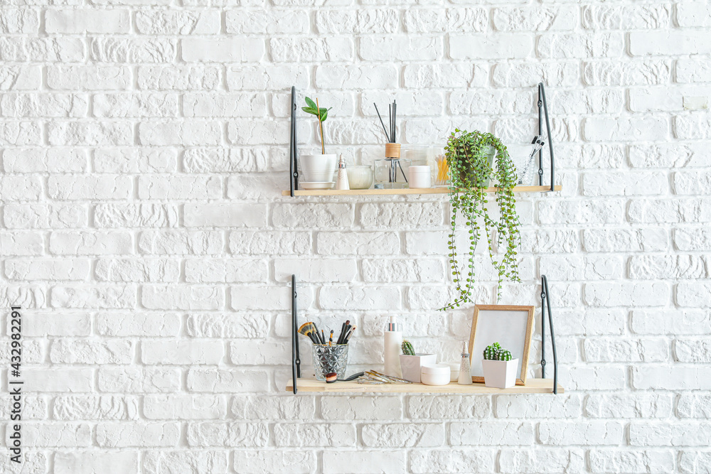 Shelves with houseplants and decor hanging on brick wall