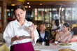 Discontented young waitress received small tips standing with money in restaurant