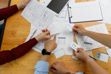 Graphic designers work together with UX UI designer planning application template layout framework for mobile phone computer mobile