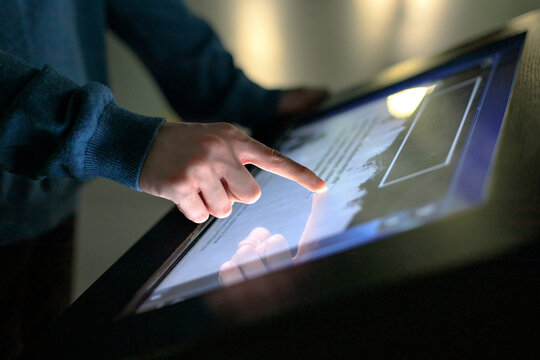 Wall Mural - A boy uses the interactive touchscreen of an electronic multimedia kiosk at a museum of modern history. Education, training and technology concept
