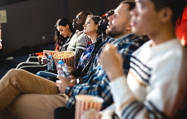 Sticker - Friends watching a movie in the cinema with popcorn. People sit in the armchairs of the cinema and look at the screen