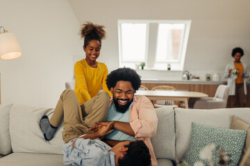 Wall Mural - Afro family in the living room. Father tickling his children