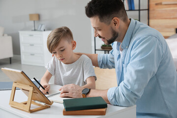 Canvas Print - Boy with father doing homework at table indoors