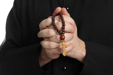 Priest with rosary beads praying on white background, closeup