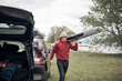 © astrosystem - Windsurfer and camper packing and unpacking from a car's roof rack in nature.