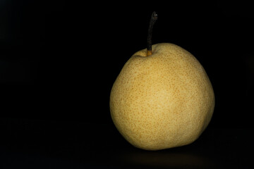 single yellow nashi pear fruit on black background