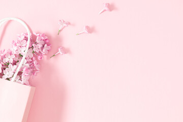Wall Mural - spring lilac flowers. gift bag and lilac branches on pink background. flat lay, top view, copy space