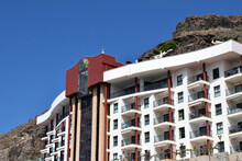 Steep Rocky Hill With Holiday Hotel In Foreground Against Blue Sky