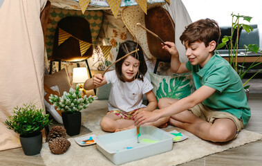 Happy children camping at home playing fishing game