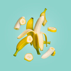 Wall Mural - Deconstructed yellow flying banana ingredients, peel and sliced parts against pastel blue background. Creative summer fruit concept. Healthy food or vegetarian diet idea.