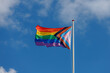 Worldwide LGBTQ community concept with progress pride flag (new design of rainbow flag) waving in the air with blue sky, Celebration of gay pride, The symbol of lesbian, gay, bisexual and transgender.