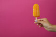 Female hand hold ice cream stick on pink background
