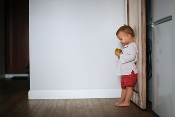 Cute baby Toddler eats tries green apple, little baby eats fruit on light background, lifestyle and cute kid, healthy eating