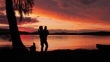 Family Vacation At Scenic Sunset Lake. Silhouettes Of Mother And Child Enjoying Beautiful View.