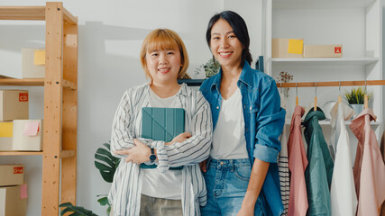 Wall Mural - Portrait of young Asia women fashion designer feeling happy smile, arms crossed and looking to camera while working clothing store in home office. Small business owner, online market delivery concept.