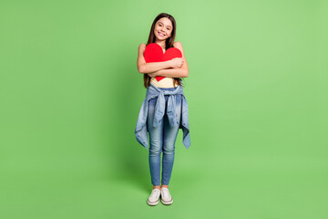 Wall Mural - Full size photo of young excited girl happy positive smile hug big red paper heart isolated over green color background