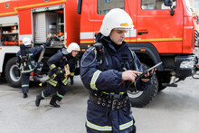 Portrait Of Firefighter In Fire Fighting Operation, Fireman In Protective Clothing And Helmet Using Tablet Computer In Action Fighting.
