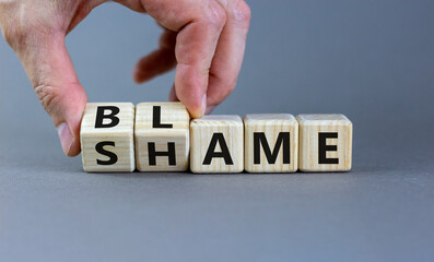 Blame or shame symbol. Businessman turns wooden cubes and changes the word 'shame' to 'blame' or vice versa. Beautiful grey background, copy space. Business, blame or shame concept.