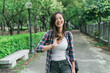 Happy lifestyle portrait of beautiful young model asian girl with sweet smile in summer casual wears. chinese woman walking with hands touching hair in city park on pathway. female face camera.