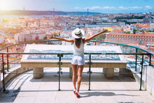 Tourist Attractions. Young Carefree Woman Tourist In White Clothes And Hat With Open Arms Enjoying The View Of Lisbon City From Viewpoint At Sunny Summer Day. Travel, Vacation And Holidays Concept. 