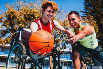 latin young man using wheelchair and playing basketball with a mexican friend in a disability concept