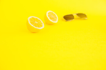 Two halves of lemon on neon yellow color and sunglasses. It's summer, enjoy. Summer is coming. Minimalist photo showing the serenity of flight. Self-care and eat summer fruit. .