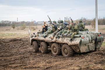 armored personnel carrier with military drives off-road on outskirts of the city