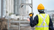 © zephyr_p - Asian maintenance worker man with safety helmet and reflective suit carrying aluminium step ladder at construction site. Civil engineering, Architecture builder and building service concepts