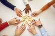 © Studio Romantic - Group of diverse people arrange human figures in circle. Team of multiethnic business partners join little wooden figures on table. Teamwork, community, working together and cooperation metaphor