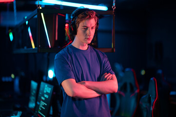 Wall Mural - Before the start of the cyber tournament, a young player poses against the background of his team's playing places