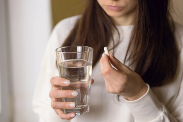 Wall Mural - The woman is being treated, holding a glass of water and an anesthetic pill in her hand