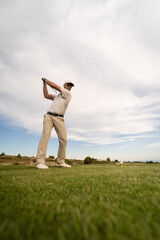 Golf player making a perfect swing on the golf course in the sunset.