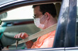 Young Man Using Cellphone Putting on Seatbelt in car  Wearing a Medical Mask