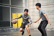 © imtmphoto - two young asian men playing basketball outdoors