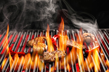 Wall Mural - Cooking of delicious beef steaks with vegetables on barbecue grill against dark background