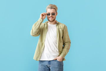 Wall Mural - Young man with stylish sunglasses on color background