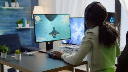 Wall Mural - African cyber gamer putting on headset before playing online video games using RGB keyboard and mouse. Player performing online games on powerful computer during gaming tournament