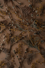 Wall Mural - Floral pattern with small mimosa flowers, juniper, pussy willow buds on brown background. Flat lay, top view