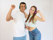 © Danko - Young couple in casual clothes listening music by headphones and dancing together over white background