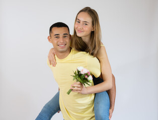 Wall Mural - Cute young couple embracing and looking the camera over white background
