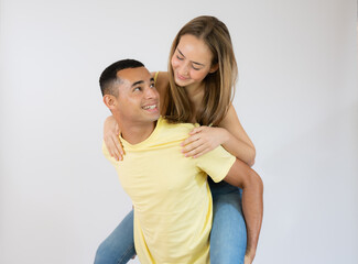 Wall Mural - Cute young couple embracing and looking each other over white background