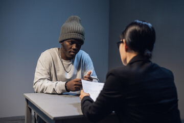 A black guy listens to his rights from a civil lawyer at a table in a visiting room in a state prison