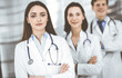 © rogerphoto - Group of young professional doctors is standing as a team with arms crossed in a hospital office and is ready to help patients. Medical help, insurance in health care, best disease treatment and
