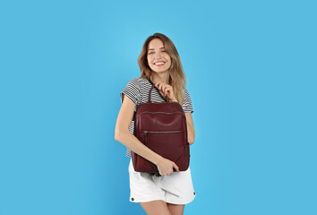 Wall Mural - Happy woman with backpack on light blue background