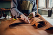 Experienced specialist in the production of footwear leather lays on a table in his workshop