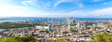 Fototapeta Miasto - Flag wavering in front of scenic view of Cartagena modern skyline near historic city center and resort hotel zone.